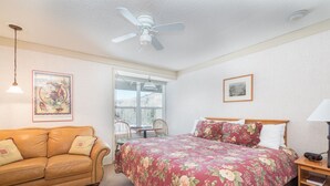 A bedroom with a bed, a couch, a ceiling fan, a window, and a framed picture on the wall. - Mountainside Inn 121 1 Bedroom Hotel Room by Alpine Lodging Telluride (Telluride)