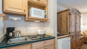 A kitchen with wooden cabinets, a microwave, a toaster, and a refrigerator. - Mountainside Inn 121 1 Bedroom Hotel Room by Alpine Lodging Telluride (Telluride)
