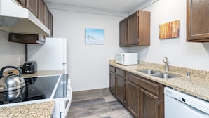 A kitchen with granite countertops, wooden cabinets, a microwave, a toaster, a stove, and a dishwasher. - Mountainside Inn 313 1 Bedroom Condo by Alpine Lodging Telluride (Telluride)