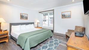 A hotel room with a bed, a desk, a chair, a TV, and two windows. - Mountainside Inn 313 1 Bedroom Condo by Alpine Lodging Telluride (Telluride)