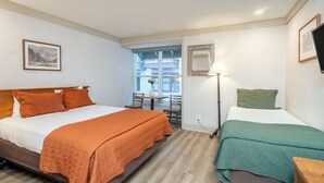 A hotel room with a large bed, a smaller bed, a desk, and a window with a view of buildings. - Mountainside Inn 315 1 Bedroom Hotel Room by Alpine Lodging Telluride (Telluride)