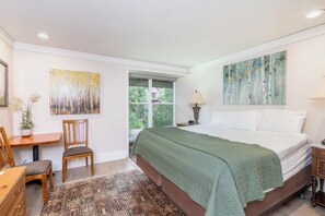 A bedroom with a bed, a desk, a chair, a window, and artwork on the walls. - Mountainside Inn 221 1 Bedroom Hotel Room by Alpine Lodging Telluride (Telluride)