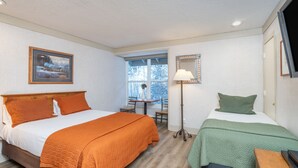 Une chambre d’hôtel avec deux lits, une fenêtre, une table et une lampe.