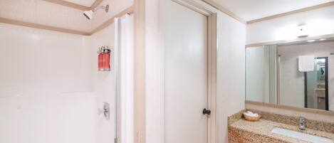 A bathroom with a white door, a sink with a granite countertop, and a mirror above the sink.