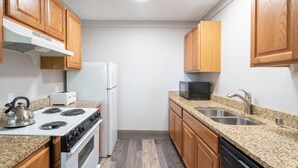 A compact kitchen with wooden cabinets, a white stove, a microwave, and a sink. - Mountainside Inn 222 1 Bedroom Condo by Alpine Lodging Telluride (Telluride)