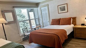 A bedroom with a bed, a bedside table, a chair, a desk, and a window. - Mountainside Inn 117 1 Bedroom Hotel Room by Alpine Lodging Telluride (Telluride)