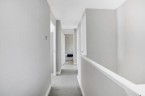 Enter a space with a door and window, featuring a carpeted floor and white walls.