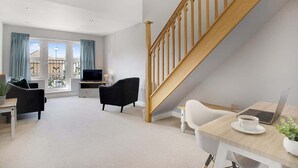 A modern living room with a staircase, a TV, a laptop, and a coffee table. - Duplex apartment, close to A1, private car park (Darlington)