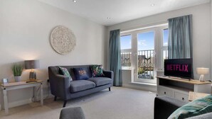 A modern living room with a sofa, a TV, and a window with curtains. - Duplex apartment, close to A1, private car park (Darlington)