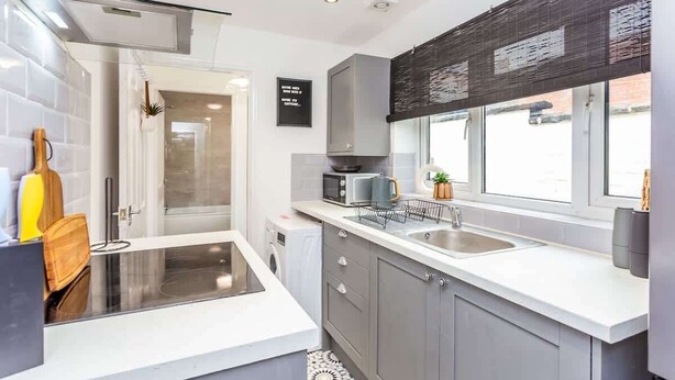 A modern kitchen with a glass enclosure, grey cabinets, a microwave, and a sink.
