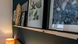 A wall with framed artwork, a decorative wall piece, and a lamp.