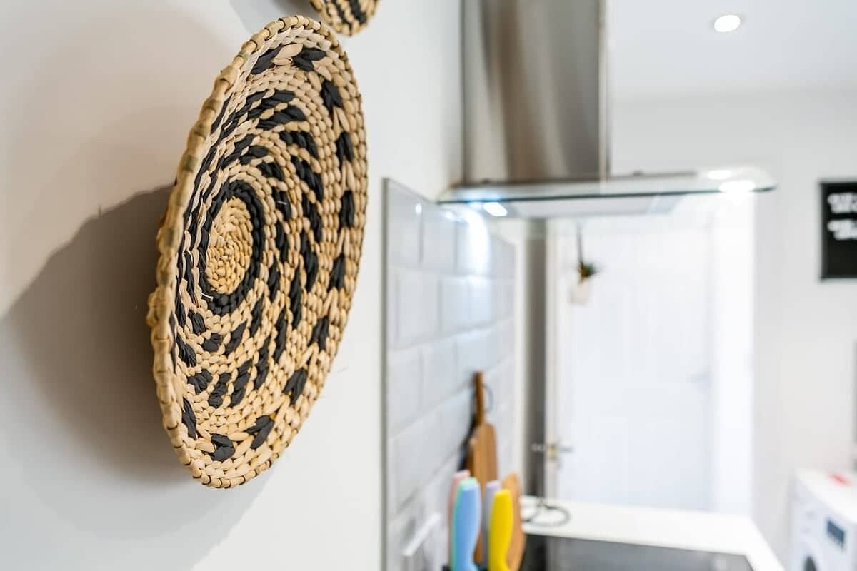 Une décoration murale tissée dans une salle de bain moderne, avec des carreaux blancs et une douche en acier inoxydable.
