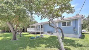 A single-story house with a covered porch, a satellite dish, and a lawn with trees. - Seashell Memories 2 Bedroom Home by RedAwning (Rockport)