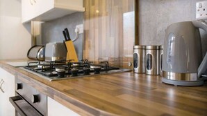 A kitchen with a gas stove, stainless steel appliances, and wooden cabinetry. - Family House near Durham & Newcastle (County Durham)