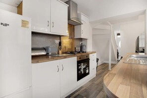 Una cocina moderna con armarios blancos, horno empotrado y encimera de madera.