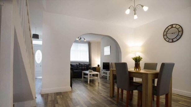 A dining area with a wooden table and chairs, a television, and a clock on the wall. - Family House near Durham & Newcastle (County Durham)