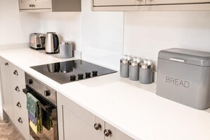 A modern kitchen with a built-in stove, a coffee maker, and a bread box.