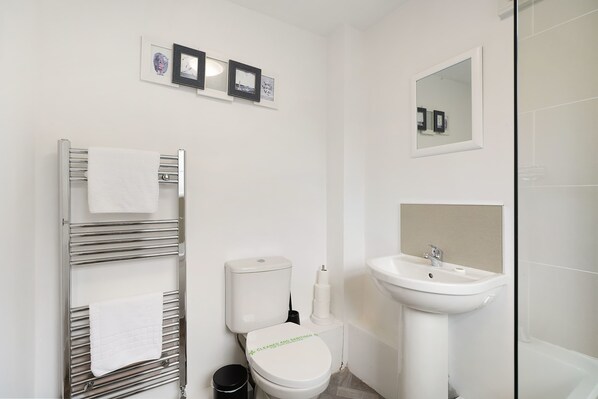 A modern bathroom with a toilet, sink, and towel rack.