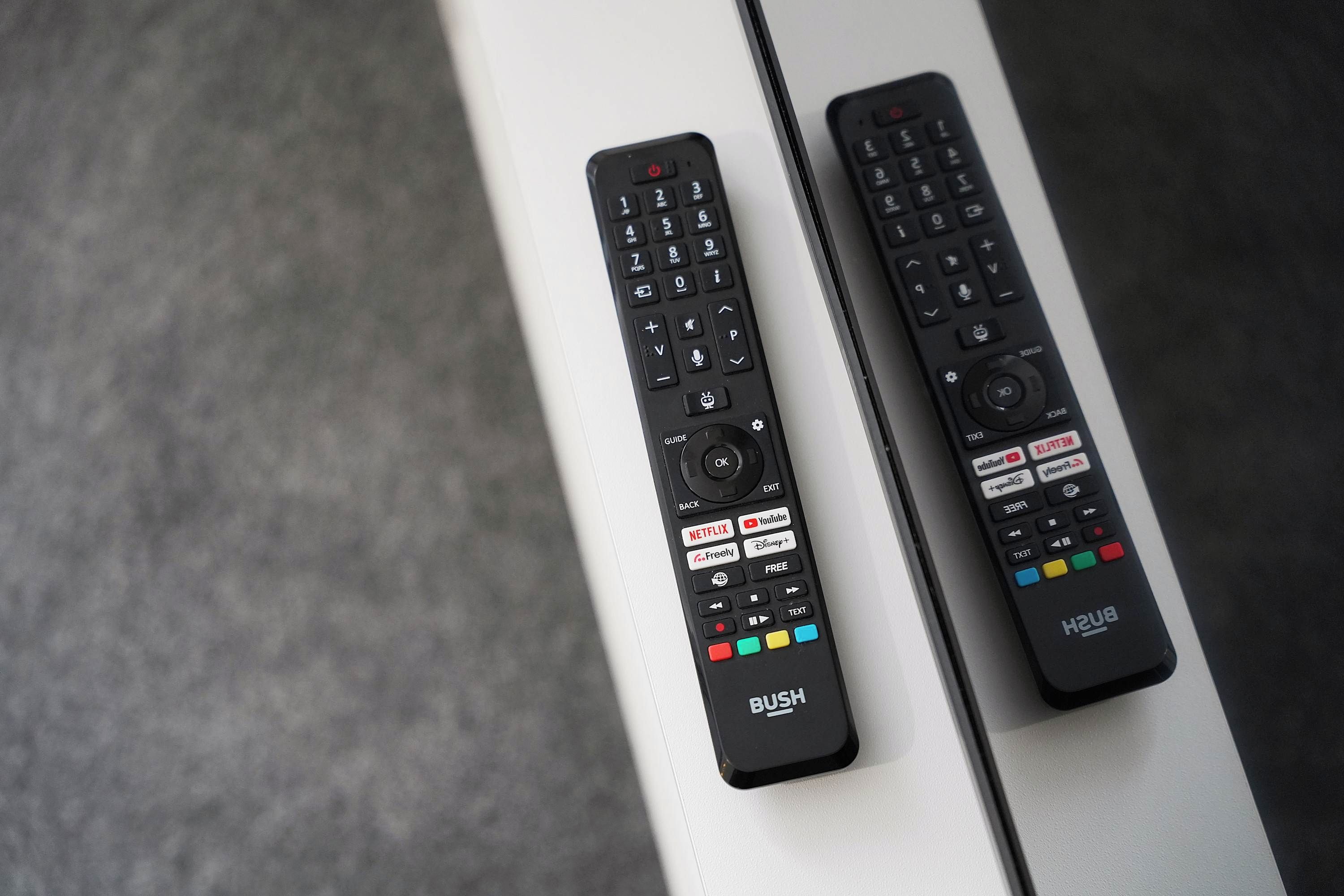 Two remote controls placed on a white surface.