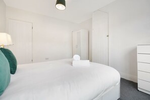 Een hotelkamer met een bed, een dressoir, een spiegel en een lamp.