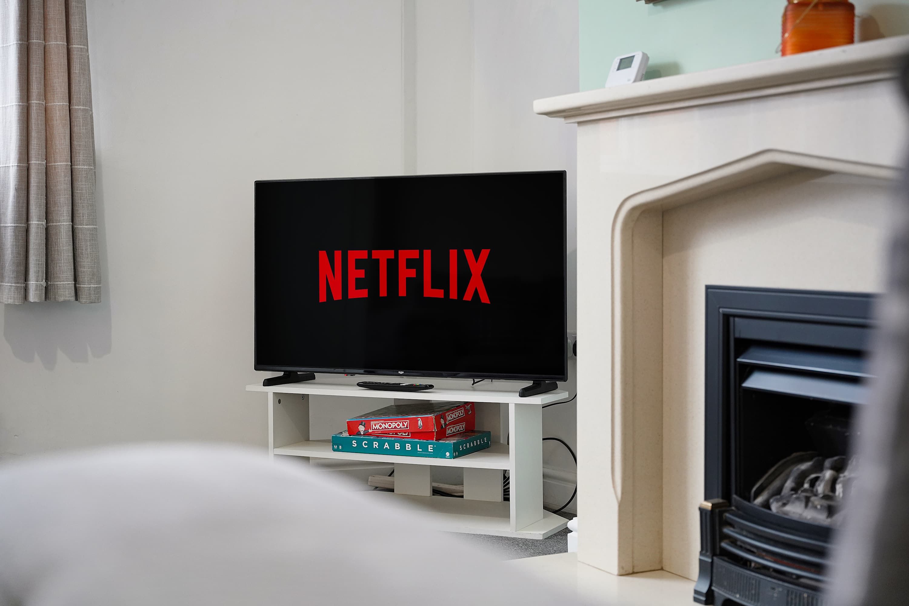 A television with the Netflix logo on the screen, placed on a white stand in a living room.