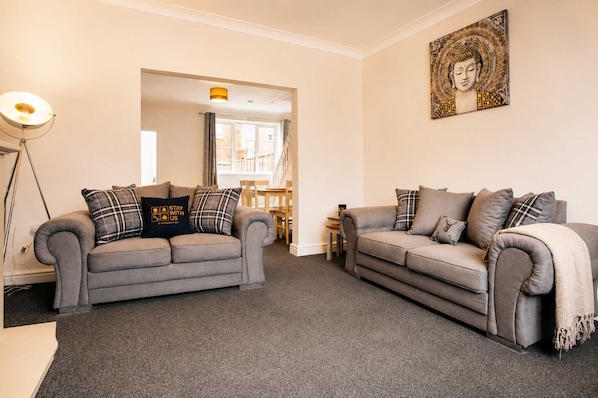 A living room with two grey sofas, a floor lamp, and a Buddha painting on the wall.