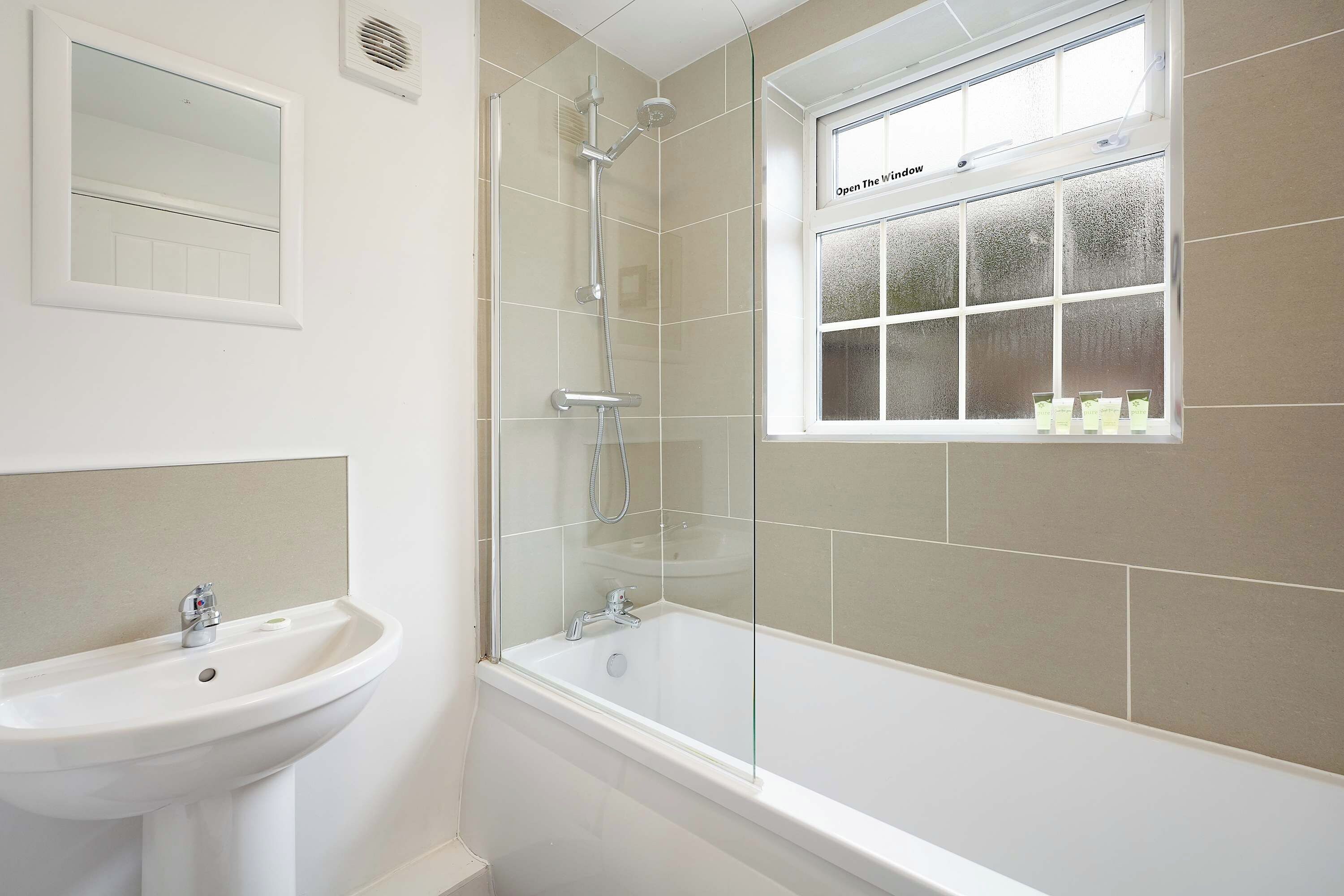 Ein Badezimmer mit Badewanne, Dusche, Waschbecken und Fenster.