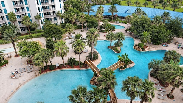 Un complexe hôtelier doté de plusieurs piscines, entouré de palmiers et comprenant des espaces de détente.