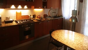 Une cuisine avec des meubles de rangement en bois, une cuisinière à gaz et un coin repas comprenant une table et des chaises.