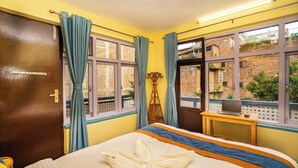 Une chambre d’hôtel avec un lit, un bureau doté d’un ordinateur portable et une vue sur un immeuble en briques par la fenêtre.
