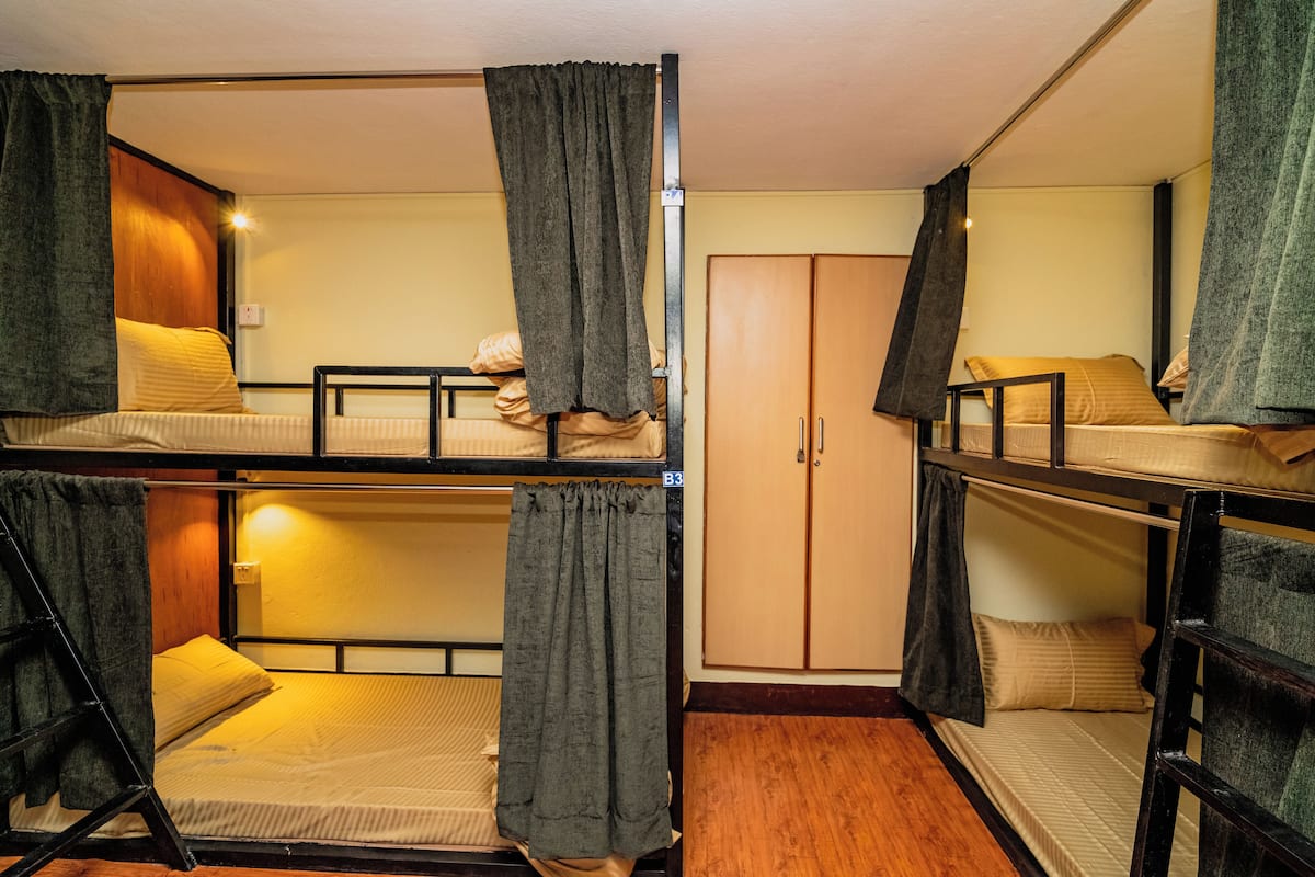 Ein Schlafsaalzimmer mit Etagenbetten, einem Schrank und Vorhängen.