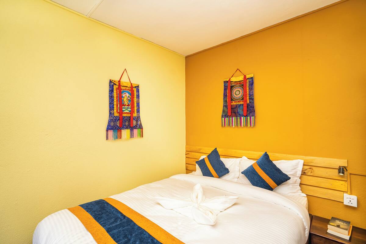 Ein Hotelzimmer mit einem Bett, Kissen, einem hölzernen Kopfteil und zwei Wandbildern.