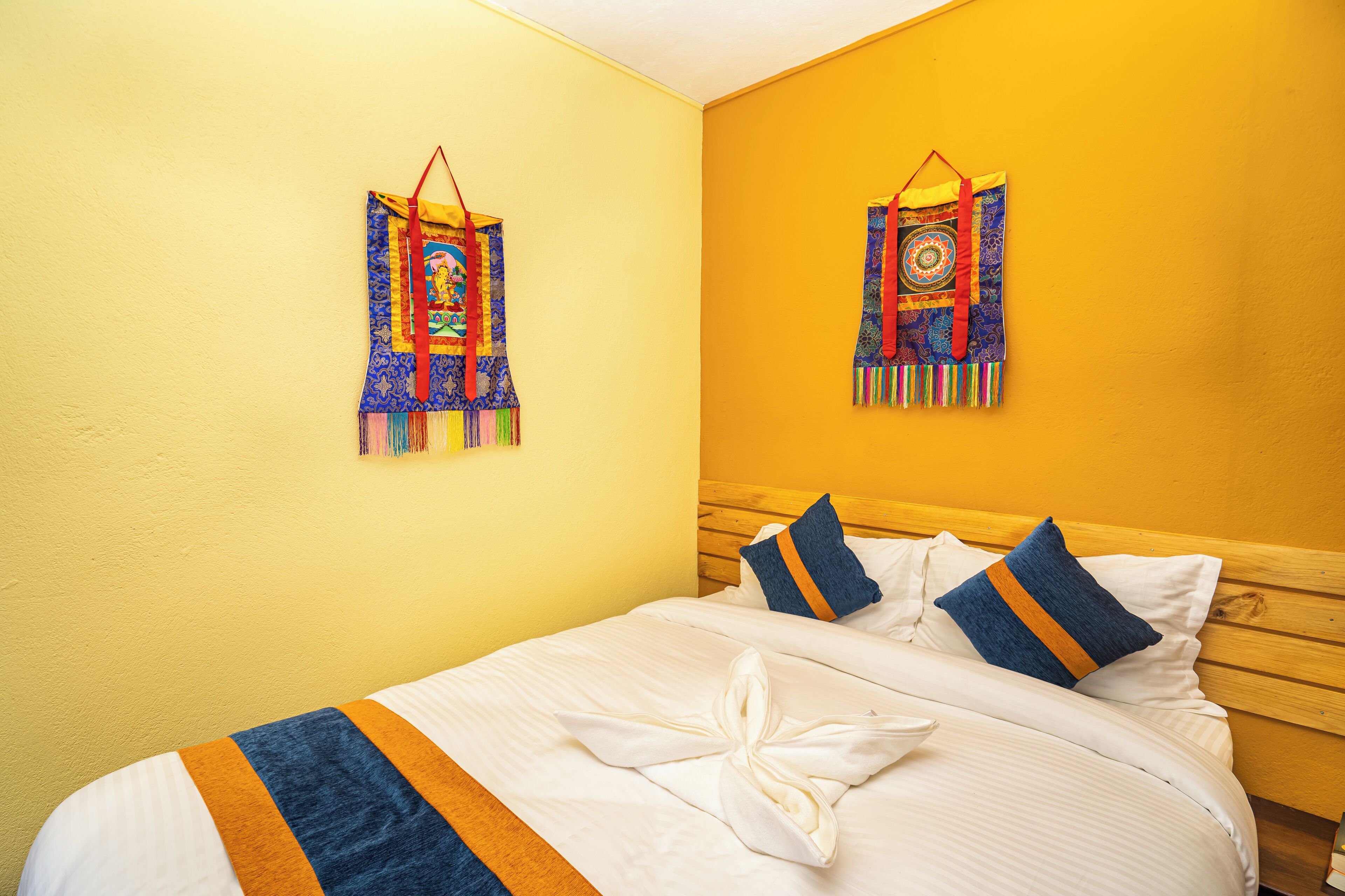A hotel room with a wooden headboard, a bed with white linens, and two decorative wall hangings.