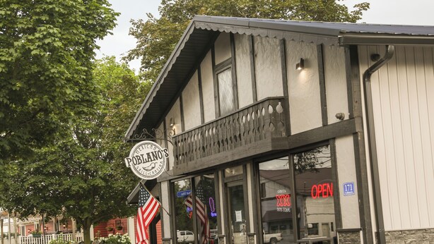 Ein Restaurant mit einem Schild, das "Poblano's Grill & Bar" zeigt, und einer amerikanischen Flagge.