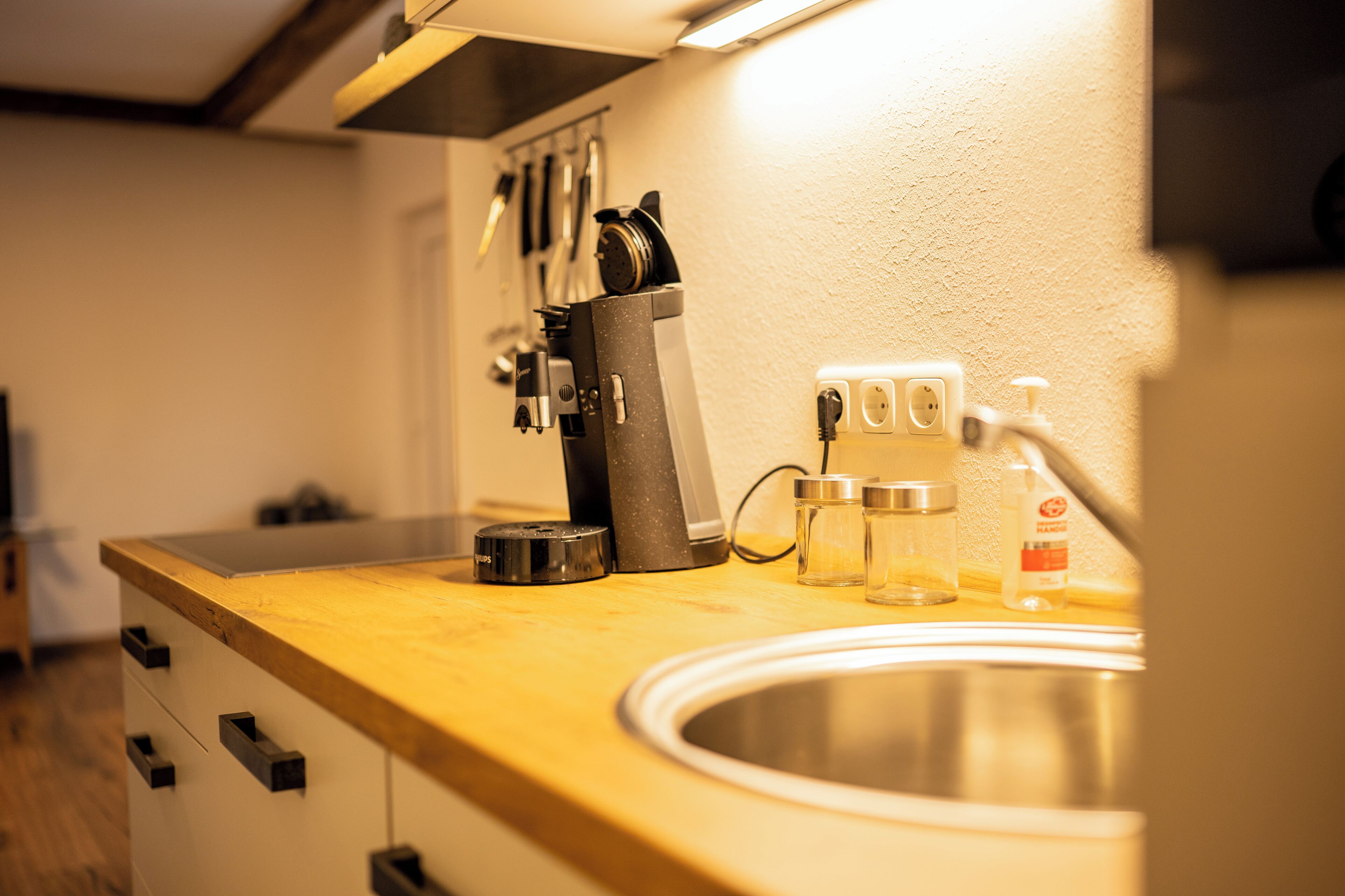 A kitchen counter with a sink, a coffee maker, and a bottle of hand soap.
