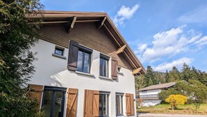 Ein zweistöckiges Haus mit geneigtem Dach, Holzhörnern an den Fenstern und einem Schotterweg.