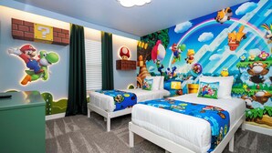 Una cameretta con due letti, una scrivania e un murale raffigurante Mario e Luigi.