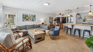 Amplia sala de estar con un sofá seccional grande, una mesa de centro y una zona de bar con taburetes.
