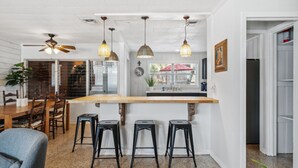 Una cocina con isla de madera, taburetes de bar e iluminación colgante.