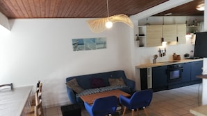 Angolo ristoro con tavolo, sedie e divano.  È presente anche una zona cucina con pensili e piano cottura.