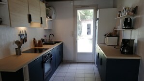 Cucina con pensili e basi blu, lavello, piano cottura e macchina da caffè.