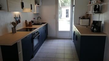 A kitchen with blue cabinets, a sink, a stove, and a coffee maker.