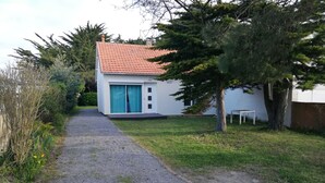 Un sentiero sterrato conduce a un edificio bianco con tetto in tegole rosse e una porta blu.