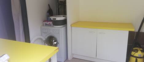 A compact laundry area with a washing machine, a drying machine, and a small cabinet with a yellow countertop.