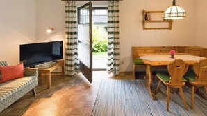 Un salón con televisor, sofá y zona de comedor con sillas y una mesa.