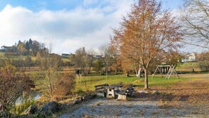 Paisaje rural con un estanque, árboles y un columpio de madera.