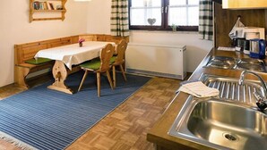Una pequeña cocina con un banco de madera, una mesa y un lavamanos.