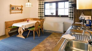Een keuken met een houten bank, een tafel met een witte tafelkleed en een gootsteen.