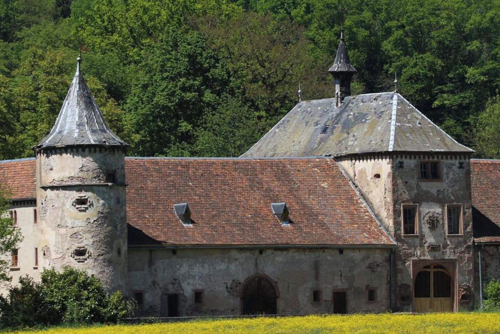 Un bâtiment historique doté d’une tour, de fenêtres en arc de cercle et d’une cour intérieure.