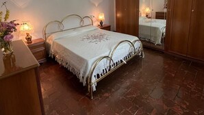 Un dormitorio con cama, lámparas de noche, cómoda, espejo y candelabro.